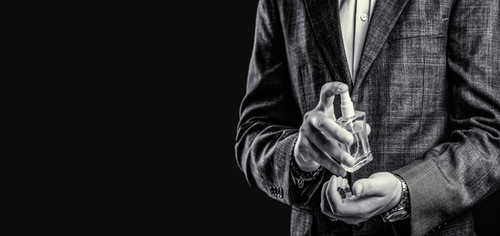 Masculine perfume, bearded man in a suit. Male holding up the bottle of perfume. Black and white